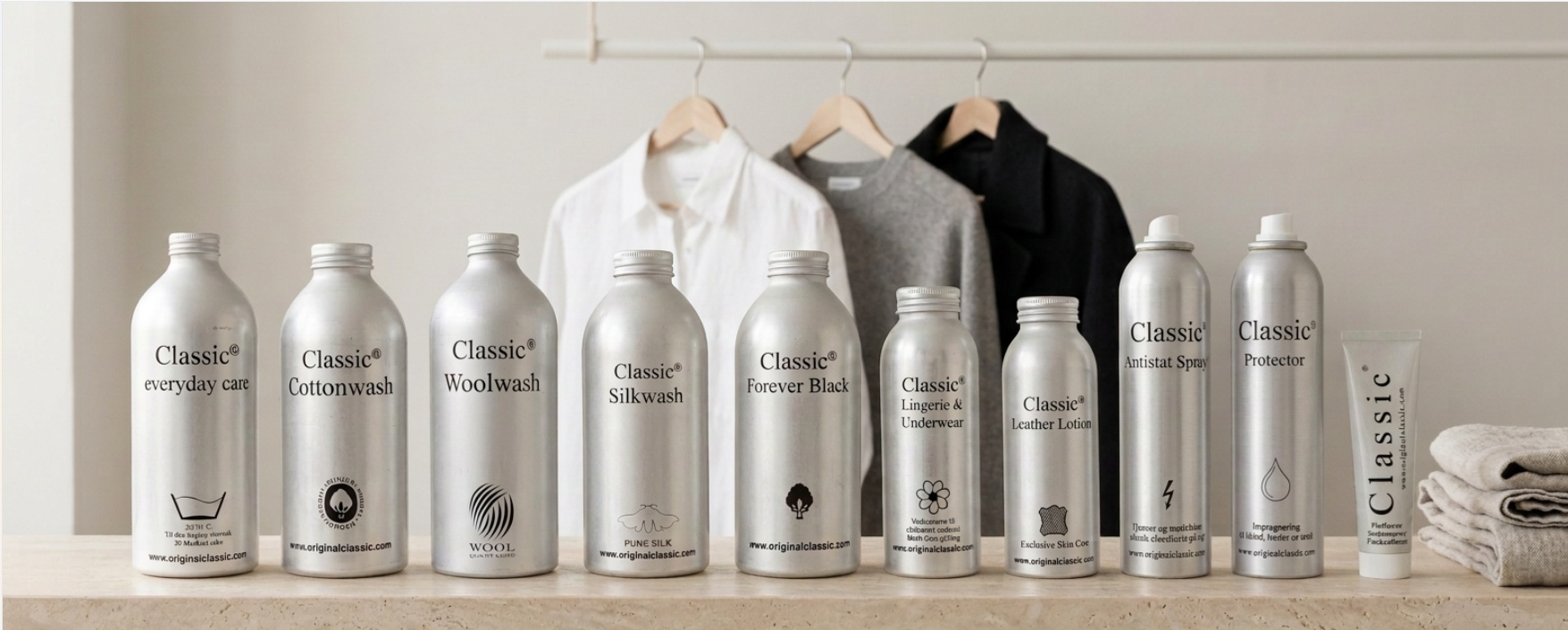 Hela Classic Clothing Care-serien uppställd på en stenhylla framför skjorta, stickat och kappa på galgar